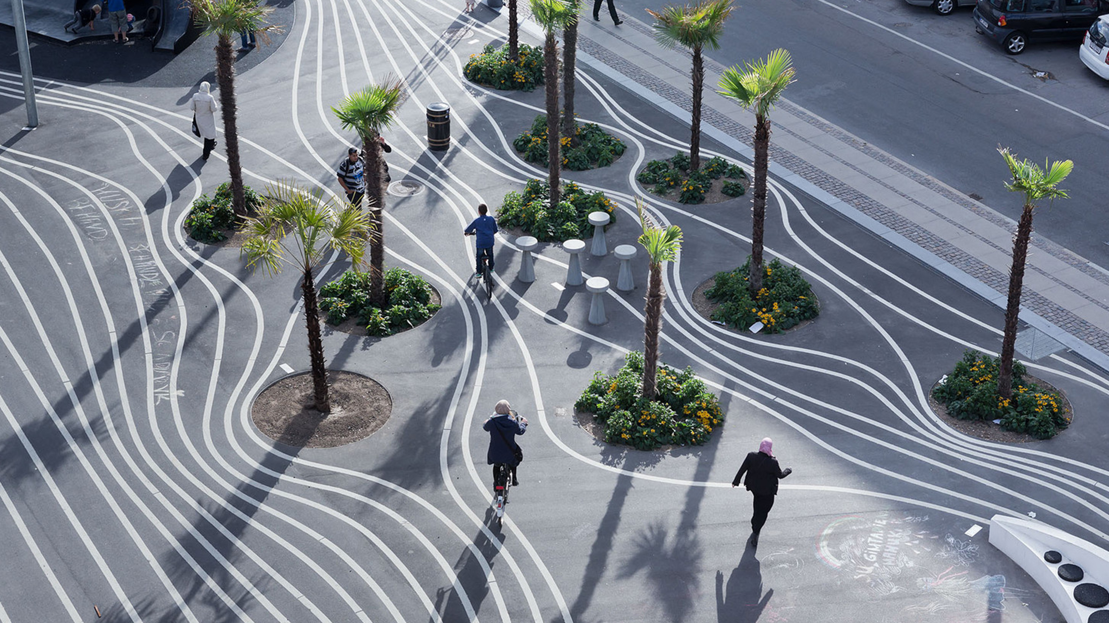 Aerial view of people on bikes around palm tree lined urban park