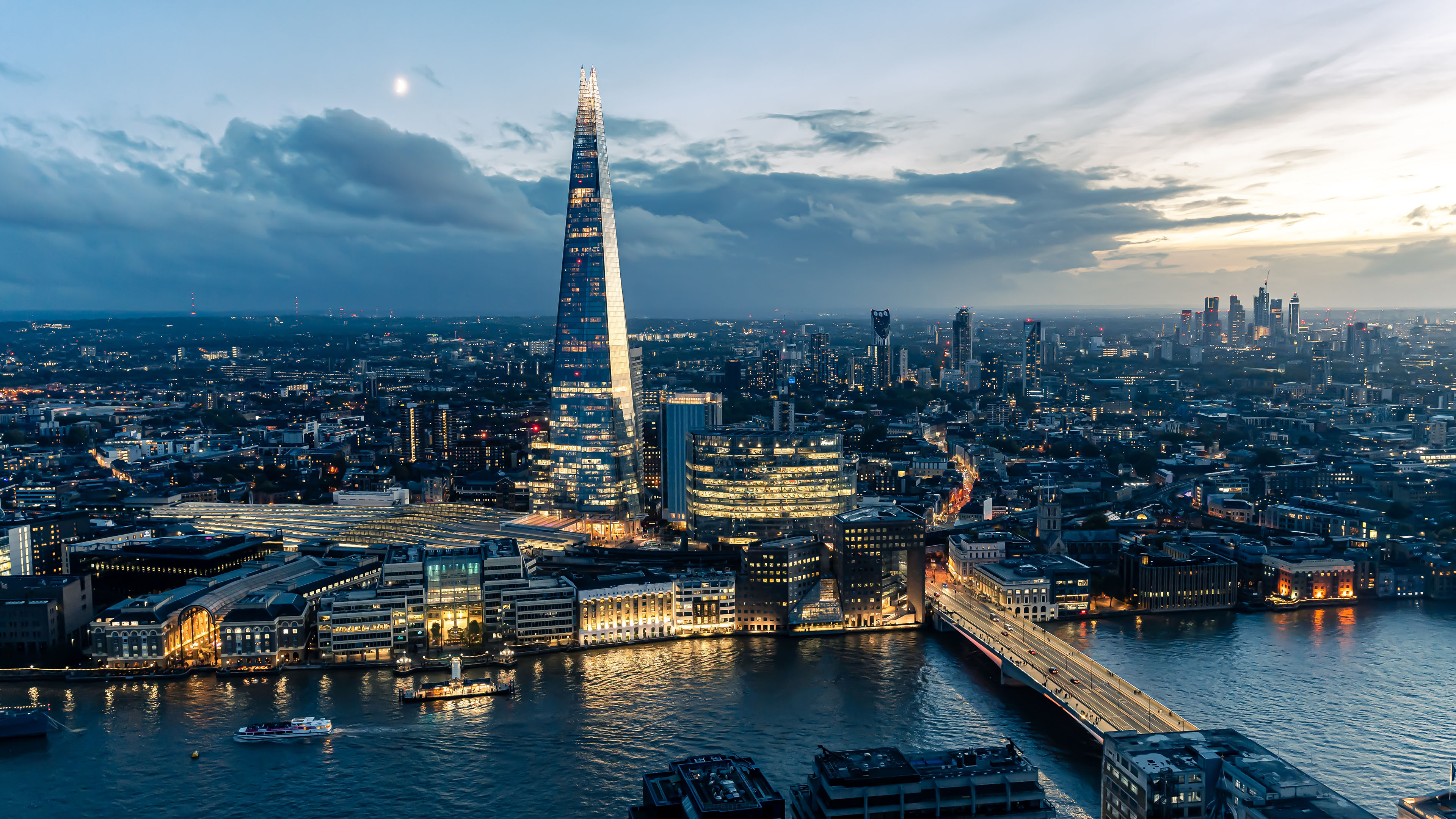 The Shard and office buildings lit up at night next to the river Thames