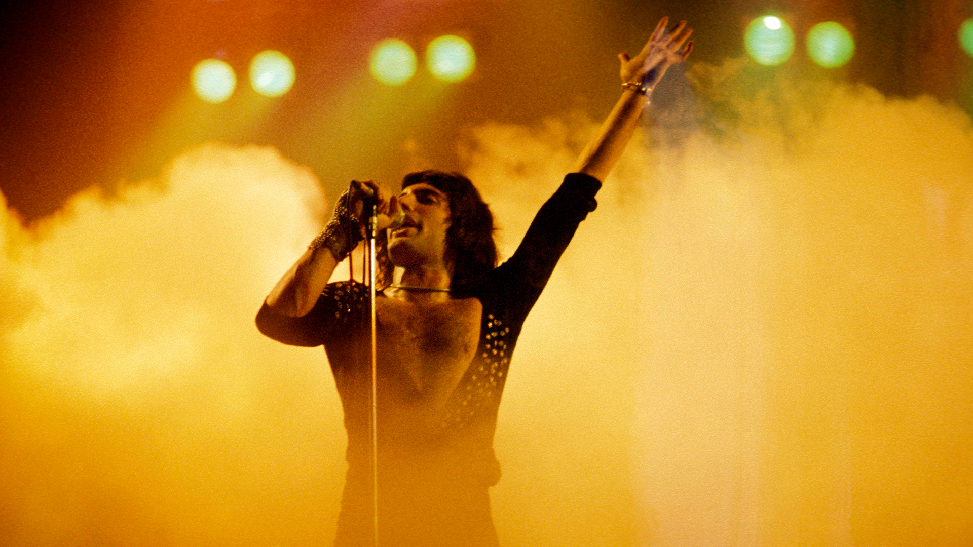 Freddie Mercury performing on stage in orange smoke