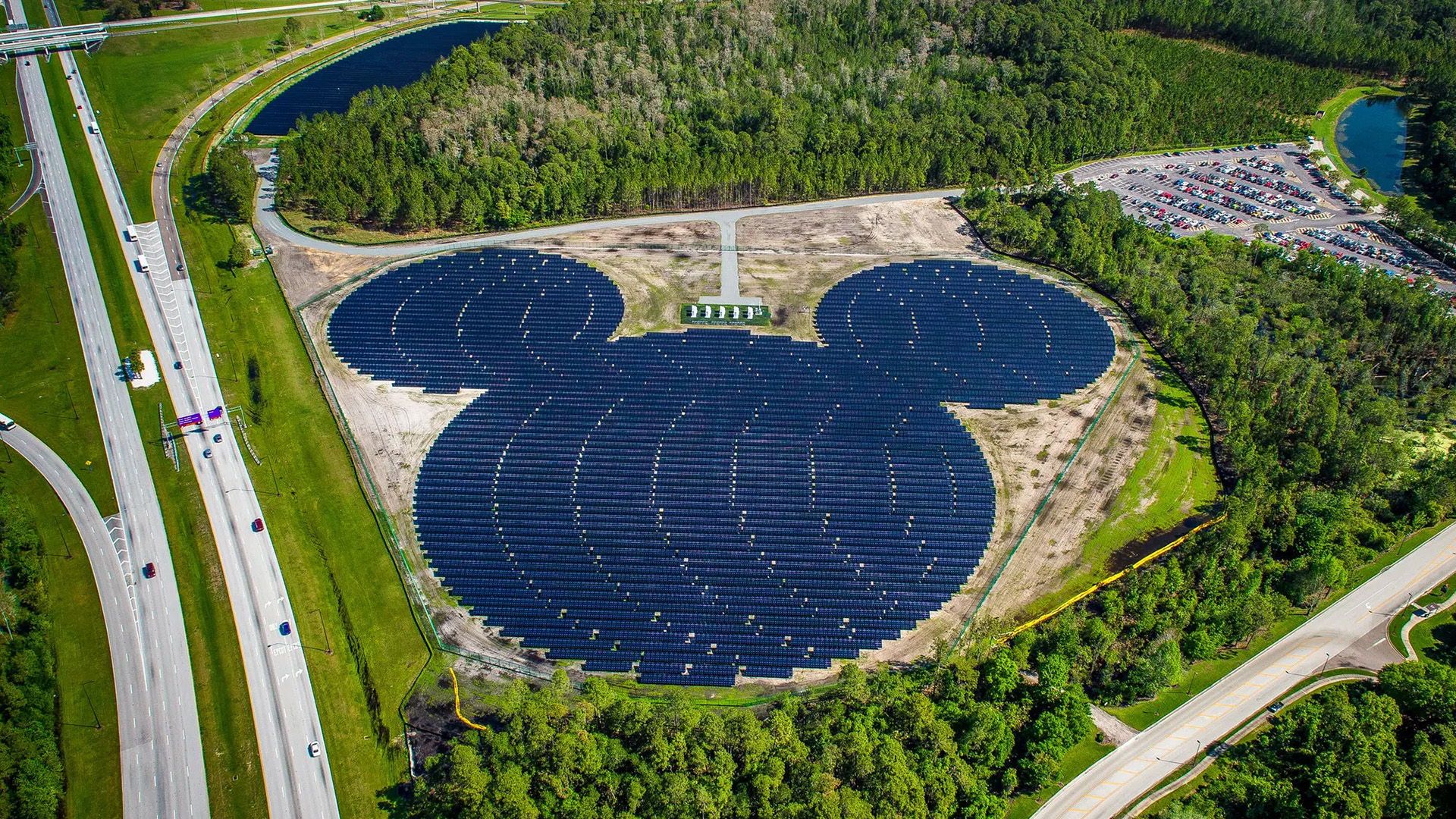 Aerial view of solar farm designed in the shape of Mickey Mouse, surrounded by trees