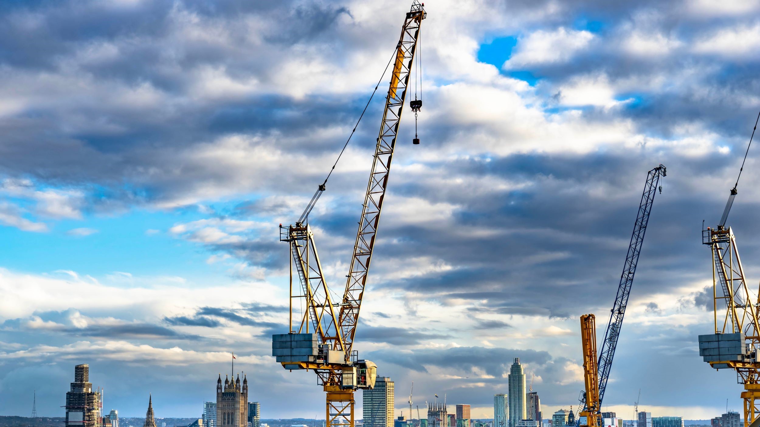 Cranes against cloudy sky