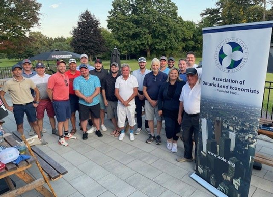 People standing next to a sign stating Association of Land Engineers in Ontario