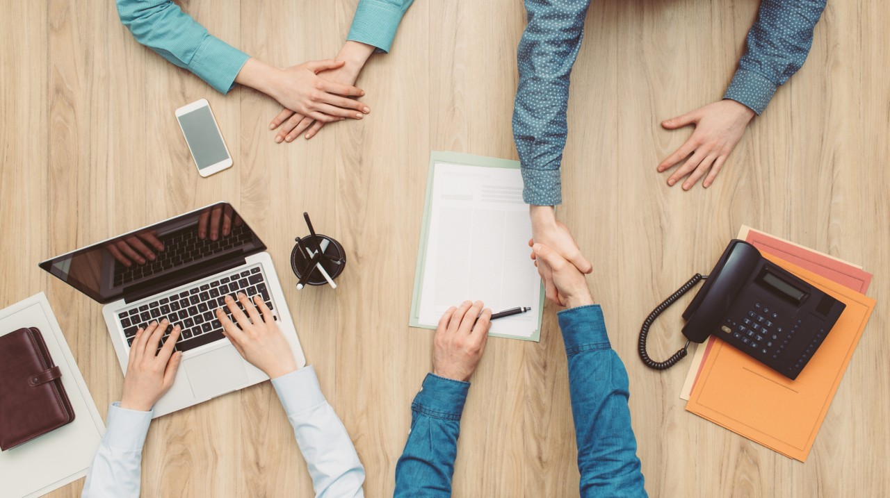 Couple having a meeting in a business office, they are signing a contract and shaking hands, top view; Shutterstock ID 620041082; purchase_order: N/A; job: RICS Mediation, Expert Witness & DRS Imagery; client: RICS_PP; other: 