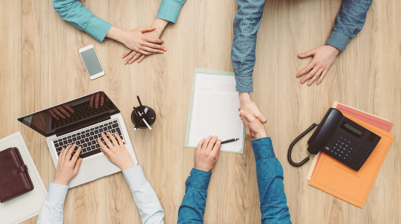Couple having a meeting in a business office, they are signing a contract and shaking hands, top view; Shutterstock ID 620041082; purchase_order: N/A; job: RICS Mediation, Expert Witness & DRS Imagery; client: RICS_PP; other: 